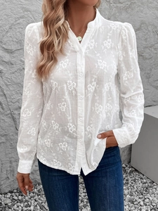 Détail d'une chemise blanche à manches longues avec broderie florale et col montant