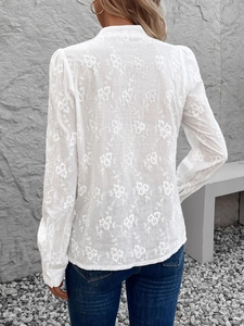 Détails de la broderie florale ajourée au dos d'un chemisier blanc à manches longues