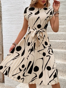 Détail de la robe plissée beige à imprimé géométrique avec ceinture sur un escalier