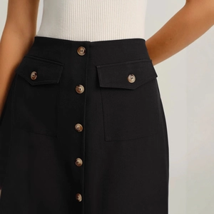 Elegant high-waist black midi skirt with amber buttons and functional flap pockets
