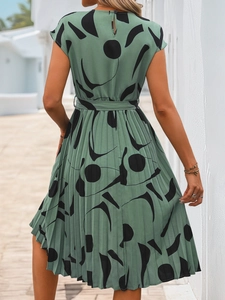 Détail d'une robe plissée verte à motif géométrique avec bouton au dos élégant