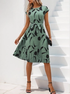 Détail d'une robe plissée vert menthe avec imprimés géométriques noirs et ceinture à nouer