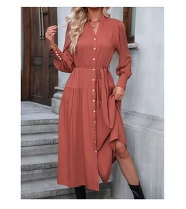 Detail of rust red shirt dress featuring V-neck, white buttons and pleated cuffs