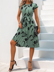 Détail de la robe plissée vert sauge avec motifs géométriques abstraits et ceinture nouée