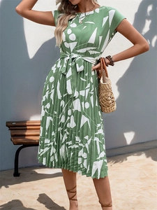 Détail d'une robe midi plissée verte avec imprimé géométrique et ceinture à nouer