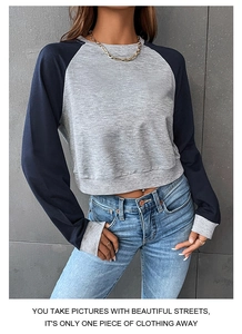 Detail eines kurz geschnittenen Sweatshirts mit grauem Strickteil und blauen Raglanärmeln