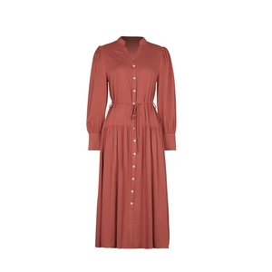 Detail of brick red V-neck dress showing white buttons and drawstring waist tie