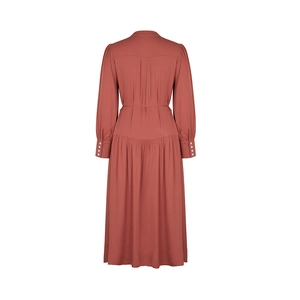 Detail view of brick red pleated midi dress featuring buttoned cuffs and high waist