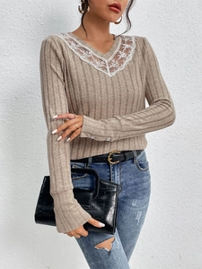 Close-up of V-neck ribbed knit sweater featuring white embroidery and button cuffs