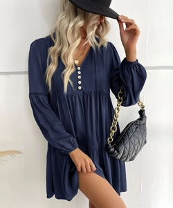 Detail of V-neck and white button accents on a navy long-sleeve dress with pleated texture