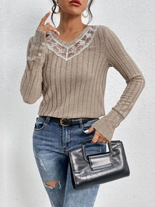 Detail of V-neck knitted sweater with white floral lace trim and grey ribbed fabric texture