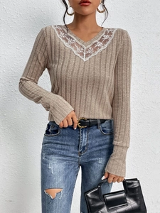 Detail of V-neckline with delicate white lace floral patchwork on oatmeal knit sweater