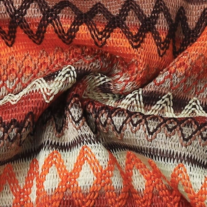 Macro shot of bohemian geometric wavy knit pattern in orange, brown and cream colors