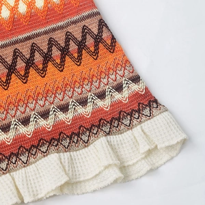 Detail of colorful bohemian knit pattern with white ruffled hem on a vacation dress