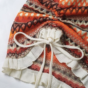 Detail of bohemian knit dress with zigzag patterns and ruffled hemline with drawstrings