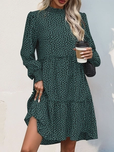 Detail of leopard print mini dress with tiered hem and ruffle high neck on green fabric