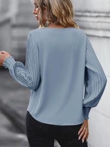 Détail de la blouse bleu clair à manches plissées avec poignets élastiques et col rond