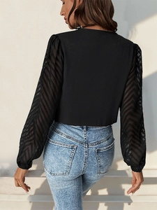 Detail of sheer mesh sleeves with chevron patterns on a black long sleeve bodysuit