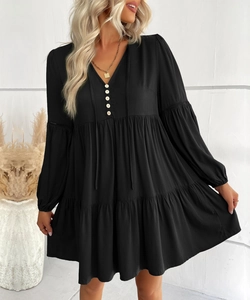 Detail of V-neckline with decorative buttons and lace patchwork on black long sleeve dress