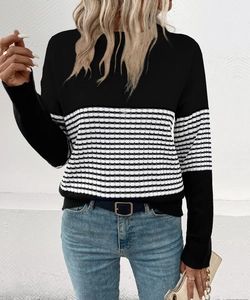 Detail of knit sweater showing black and white stripes with a solid black block design