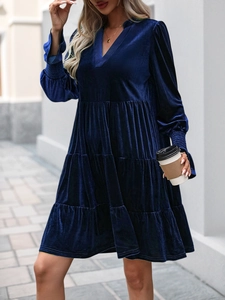 Detail of dark blue velvet tiered dress featuring a V-neck and layered ruffled hemline