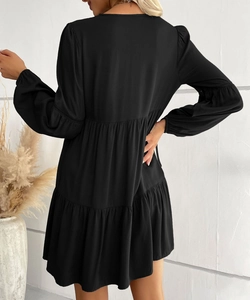 Rear view of black long sleeve mini dress featuring tiered ruffle hem and elastic cuffs