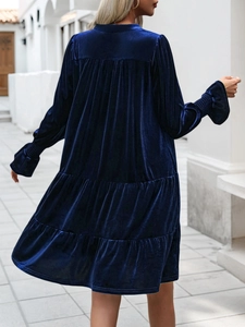 Close-up of dark blue velvet fabric texture and tiered ruffle design on long sleeve dress