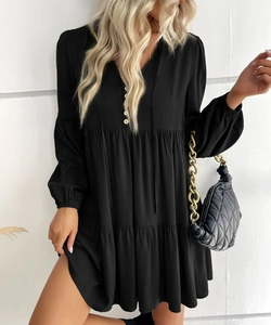 Detail of V-neckline with buttons, tie-up strings, and elastic cuffs on a black mini dress