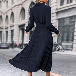 Rear view of navy blue long-sleeved pleated dress with collar and waist belt detail