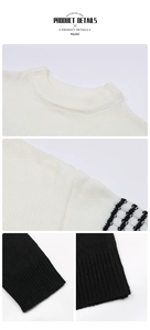 Detail view of knit sweater showing ribbed crewneck and black striped sleeve cuffs