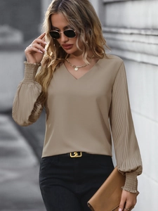 Détail des manches plissées et des poignets à volants de cette blouse beige à col en V