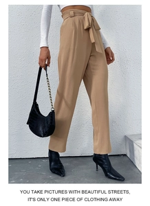 Detail of khaki high waist trousers with a tie-waist and pleated paperbag design
