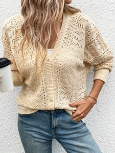 Dettaglio del cardigan in maglia crema con motivi geometrici traforati e scollo a V