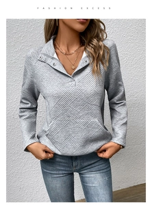 Detailansicht eines grauen Sweatshirts mit geometrischer Textur und Knopfkragen
