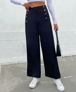 Detail of high waisted wide leg trousers featuring decorative gold vertical buttons