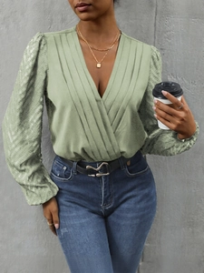 Detail of light green V-neck wrap blouse with pleated texture and puffed long sleeves