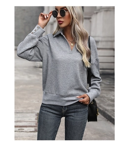 Close-up of grey textured knit sweatshirt with polo neck and buttoned cuffs details