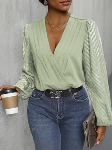 Close-up of sage green wrap top featuring V-neck pleats and sheer textured sleeves