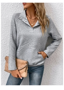 Detail eines grauen Sweatshirts mit Rautenstruktur, Reverskragen und Metallknöpfen
