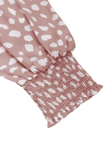 Detail of smocked cuffs and ruffle trim on long-sleeve polka dot print dress