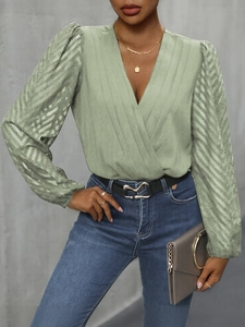 Detail of light green V-neck bodysuit with pleated fabric and sheer textured long sleeves