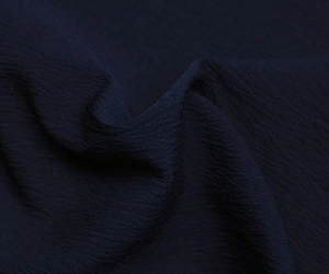 Macro detail of navy blue pleated crepe fabric with elegant wavy texture and high sheen