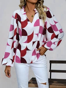 Close-up of pink and burgundy geometric print blouse with ruffled V-neck and lantern sleeves