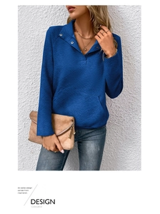 Detail eines dunkelblauen Sweatshirts mit Rautensteppmuster und Kragen mit Knöpfen