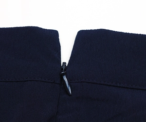 Detailed close-up of dark blue trousers featuring a hidden zipper and textured fabric