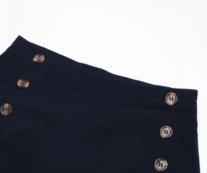 Detail of high-waist wide-leg pants with two rows of vintage tortoiseshell buttons