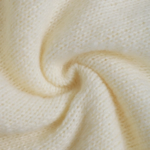 Detailed macro view of soft cream knit fabric texture with premium stitching details