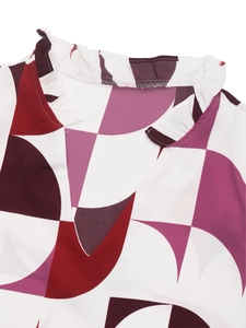 Detail of the V-neckline featuring elegant ruffles and a geometric print pattern on fabric