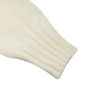 Detail view of the ribbed cuff and soft knit texture on this cream-colored sweater