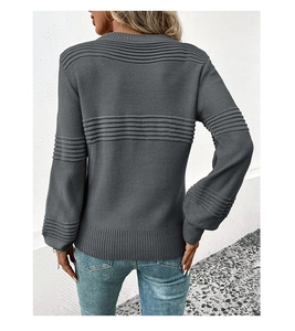 Detail of dark grey knit sweater showing 3D ribbed texture on back hem and sleeve cuffs